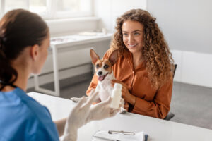 Veterinarian explaining pet medications and pet prescriptions to a smiling owner and her dog during a clinic visit.